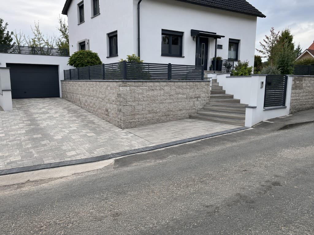 Gestaltete Außenanlagen mit Pflaster, Stützmauer und Treppenanlage