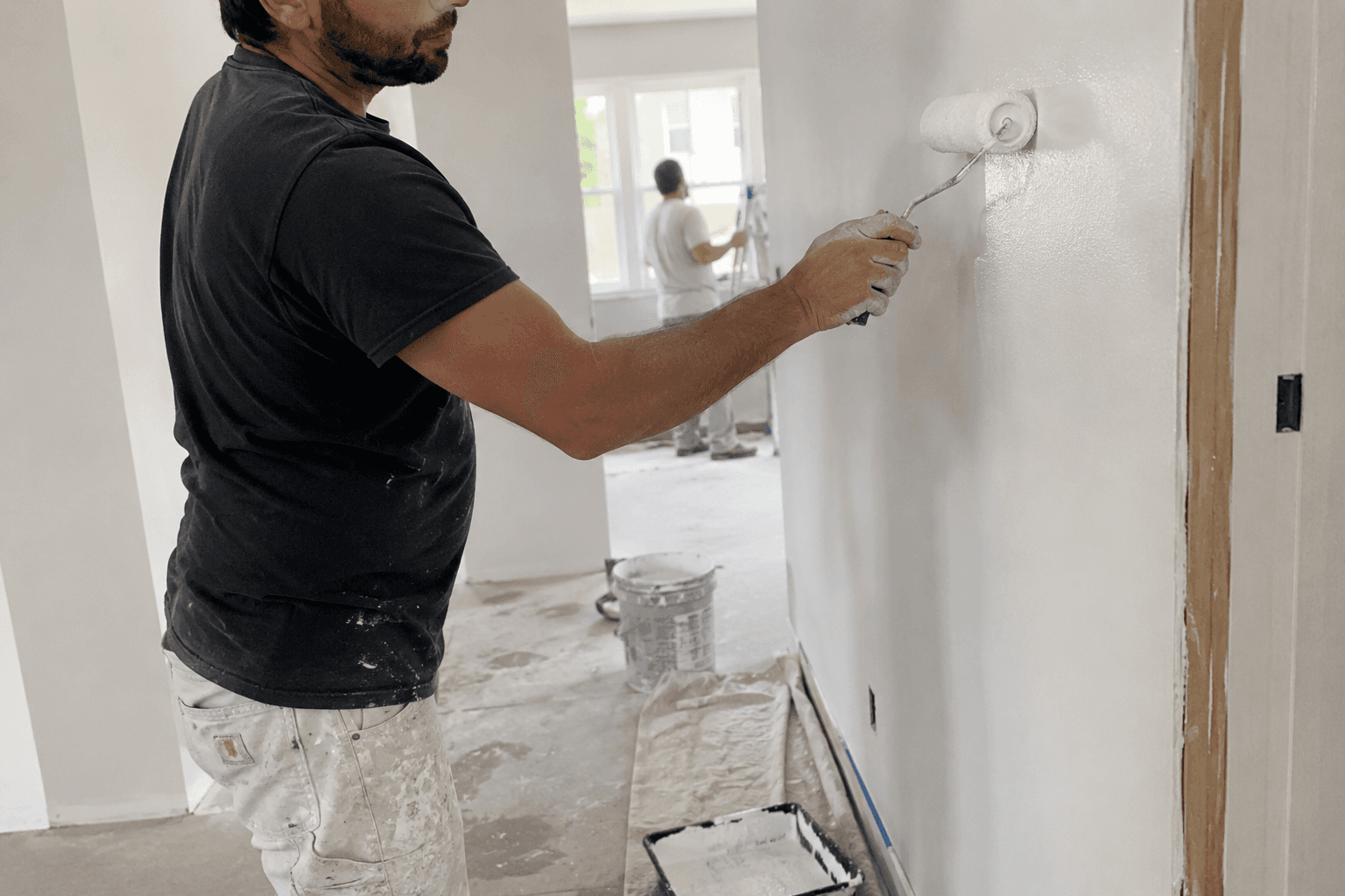 Maler streicht eine Wand mit der Farbrolle bei der Innenrenovierung